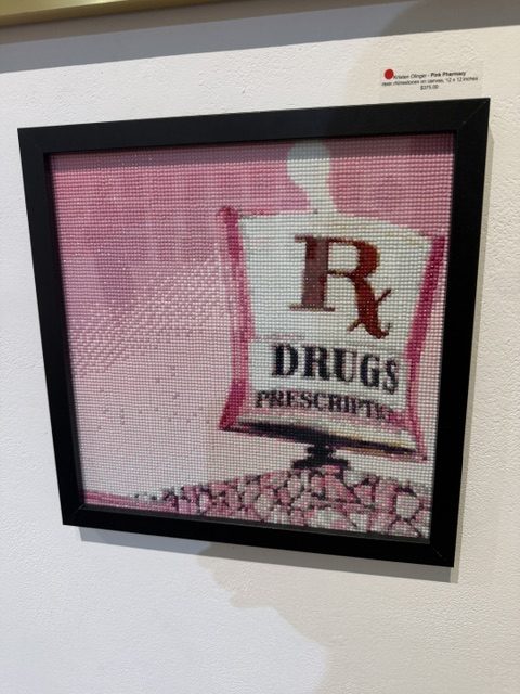 Framed pink artwork featuring a vintage-style prescription drugs sign at Laluzapalooza 2026.