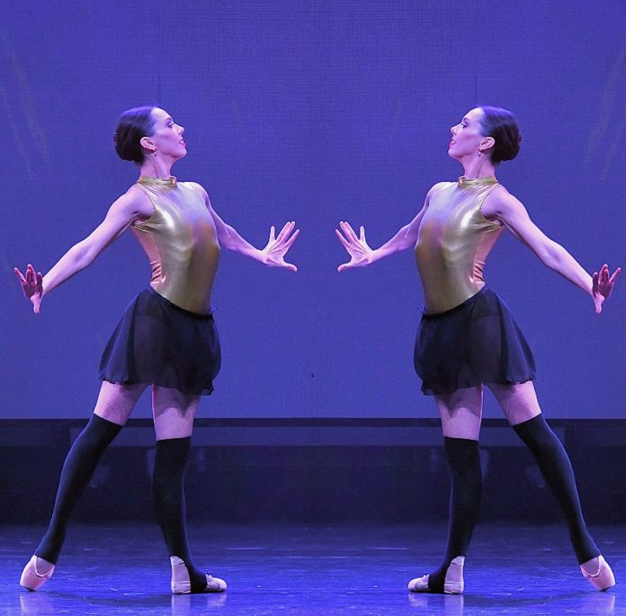 Luminario Ballet dancers performing a mirrored ballet sequence under purple stage lighting.