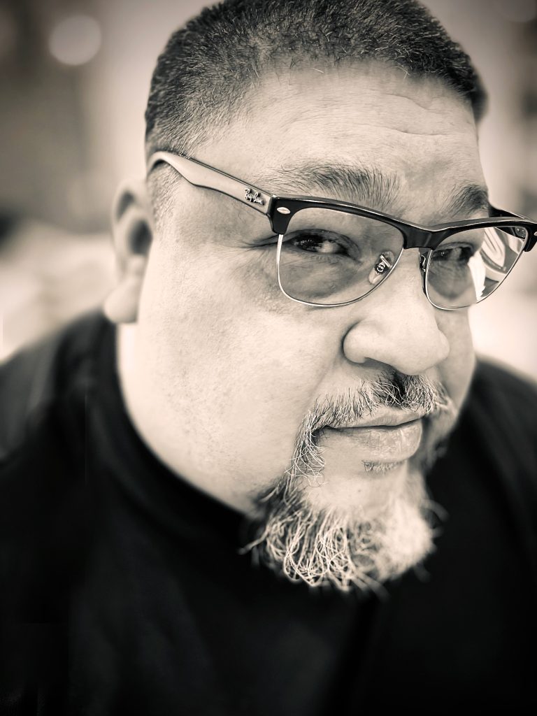 Black-and-white portrait of playwright Chris Banda, writer of DIVE BAR at CASA 0101 Theater.