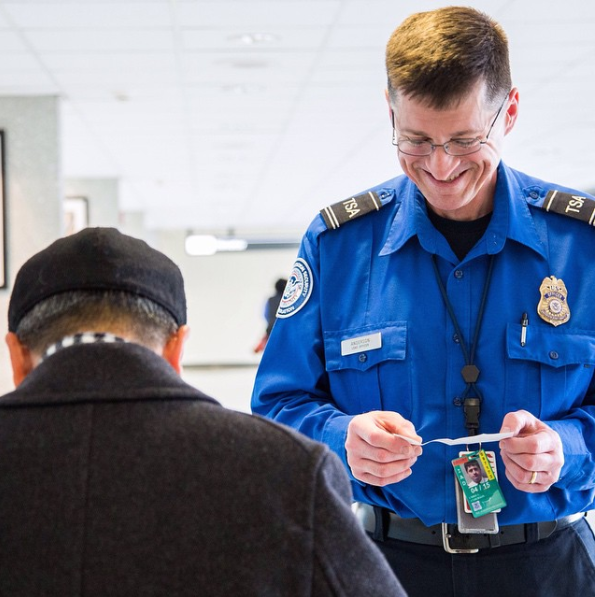 TSA officer assisting a traveler at an airport security checkpoint.