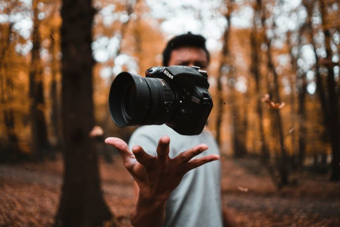 Photographer holding a camera in an autumn forest, illustrating how individual photos can become part of a larger visual story.