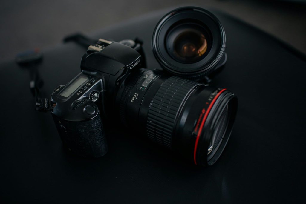 Professional DSLR camera and camera lenses arranged against a dark background, illustrating photography and artistic photo collage creation.
