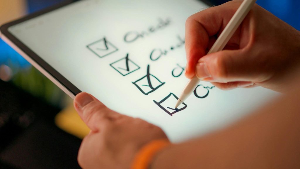 Person checking boxes on a tablet, illustrating a checklist for verifying and troubleshooting payment delays.