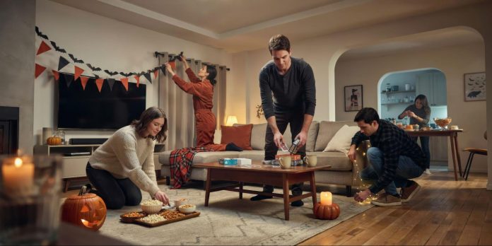 image2 Friends preparing a home for a Halloween party with pumpkins, snacks, string lights and seasonal decorations.