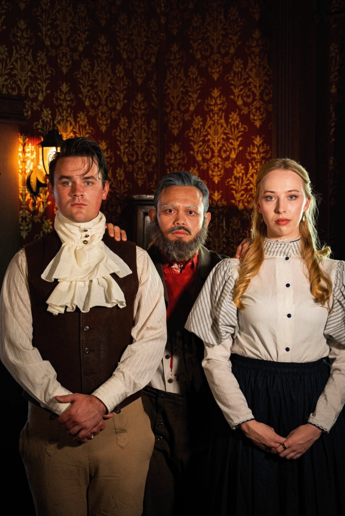 Cast members of GOTHIQUE at Zombie Joe's Underground Theatre pose in Victorian costumes inside a dark gothic manor.