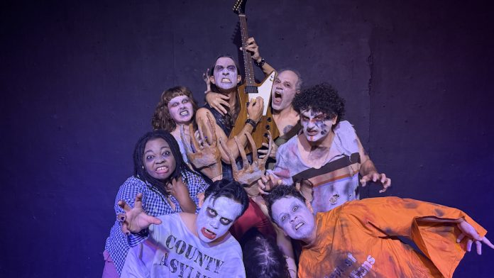 Eight performers in grotesque zombie makeup and torn costumes pose menacingly for Zombie Joe's Urban Death Tour of Terror ULTRA 2026.