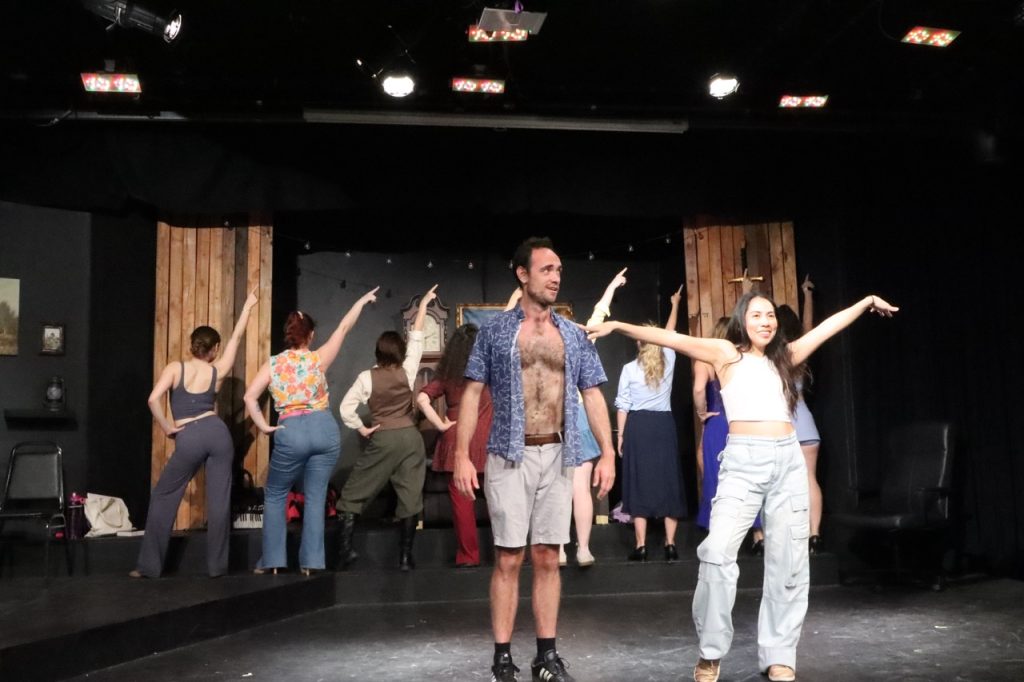 Performers sing and dance onstage during Malice in Malibu, the world premiere musical comedy at Above The Curve Theatre.
