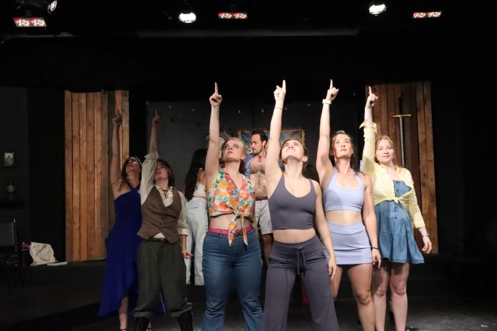Female ensemble performs synchronized choreography in Malice in Malibu, a musical murder mystery presented by Above The Curve Theatre.