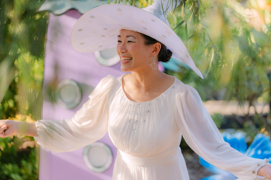 Mindy Le performs in a white Oz-inspired costume and wide-brimmed hat during Fall Into Oz.