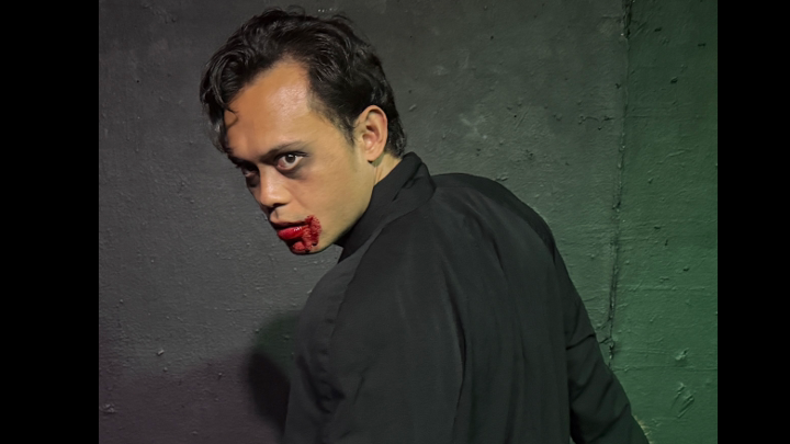 Close-up of a menacing performer in black clothing with bloodied lips in Zombie Joe's Urban Death Tour of Terror ULTRA.