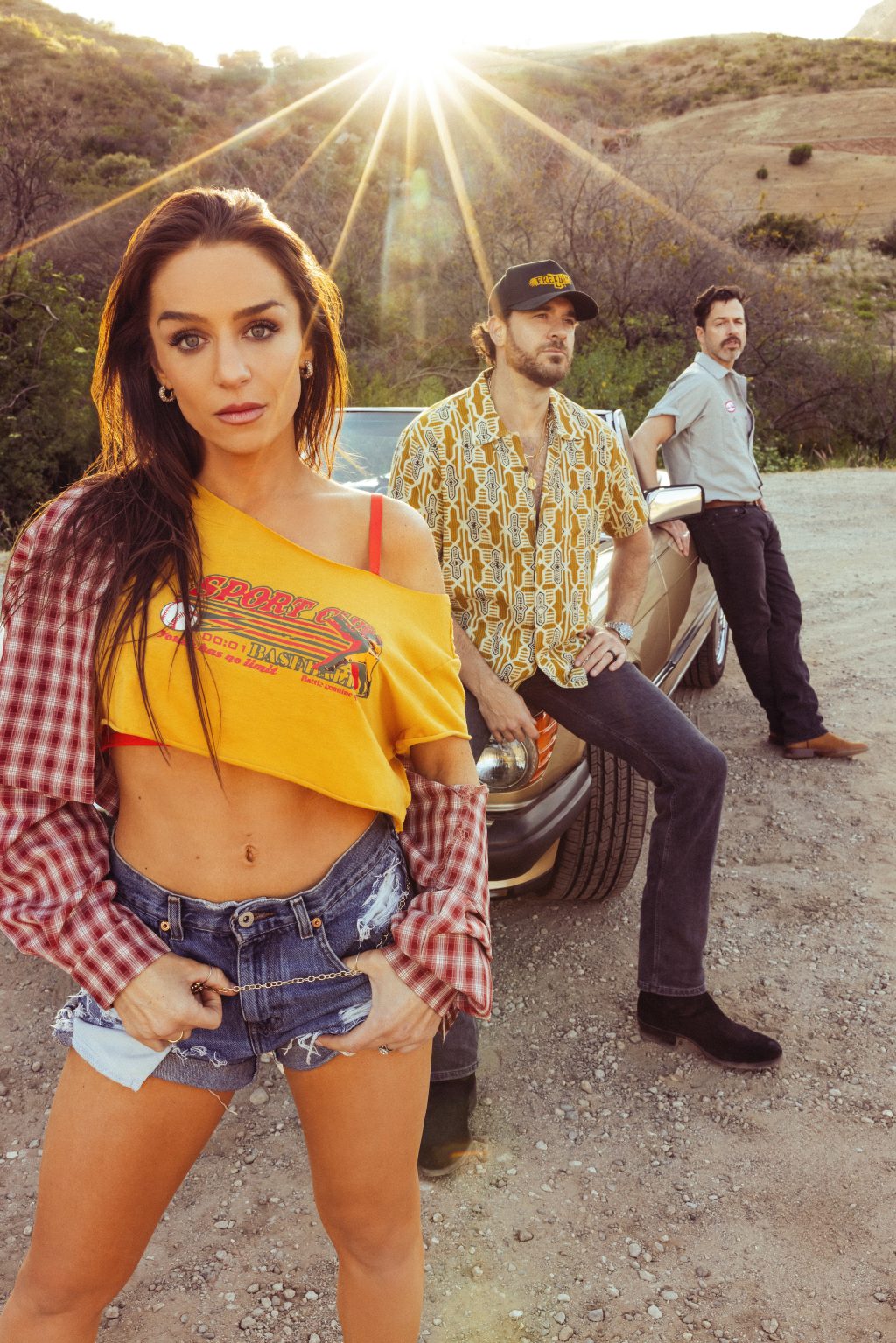 Los Angeles country-rock band RustRiders posing together beside a vintage convertible.