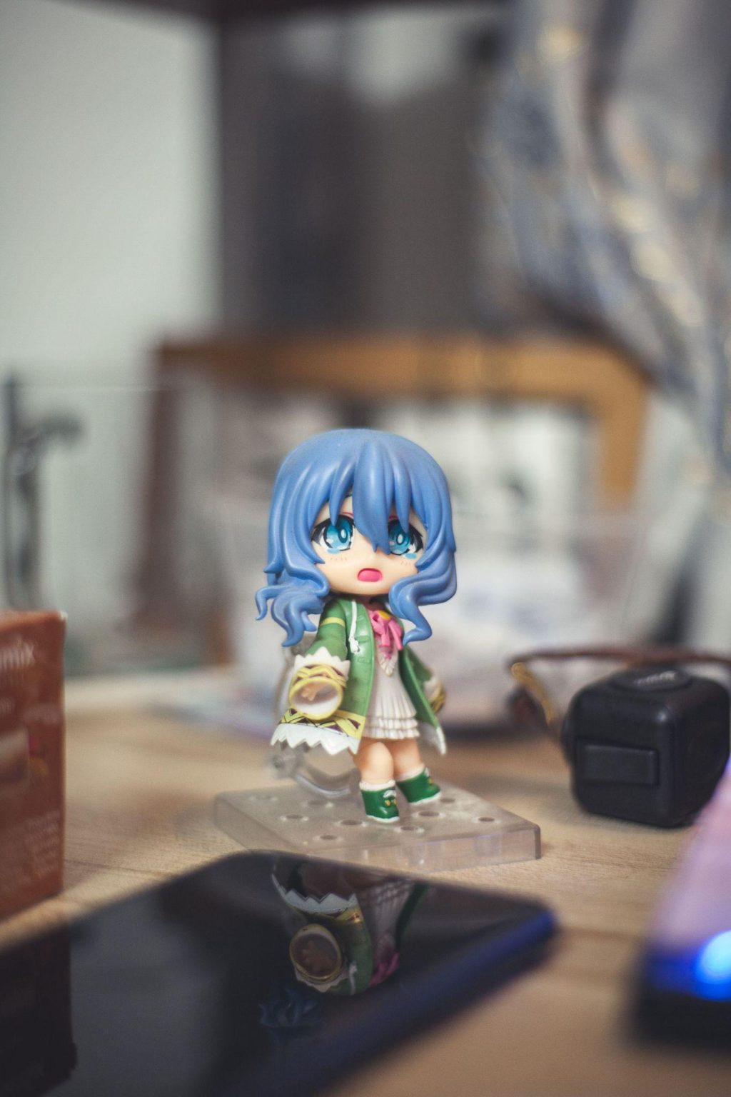 Chibi-style anime figure with long blue hair, wearing a green outfit and displayed on a clear stand.